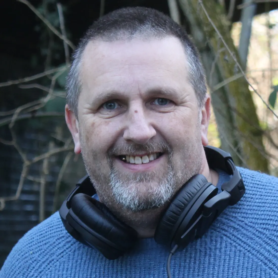 Chris Kirk smiling on location, wearing headphones